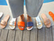 Woman wearing Sugarbird leather slide sandals in flame and navy alongside Sugarbirs in platinum and beach.