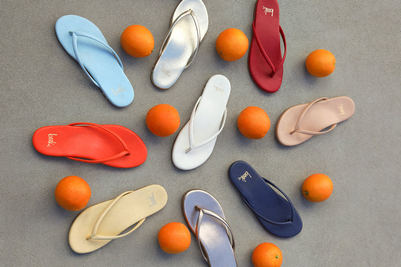Group shot of Sunbeam leather flip flop sandals in sky, flame, platinum, glow, vanilla, lipstick, beach, navy, bronze.