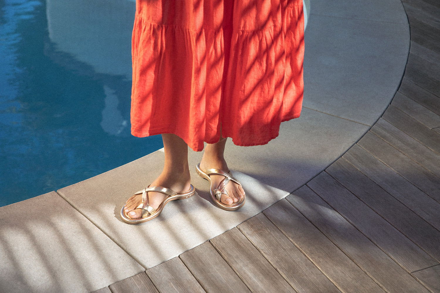 Woman wering Sungem leather toe-ring sandals in gold with red dress