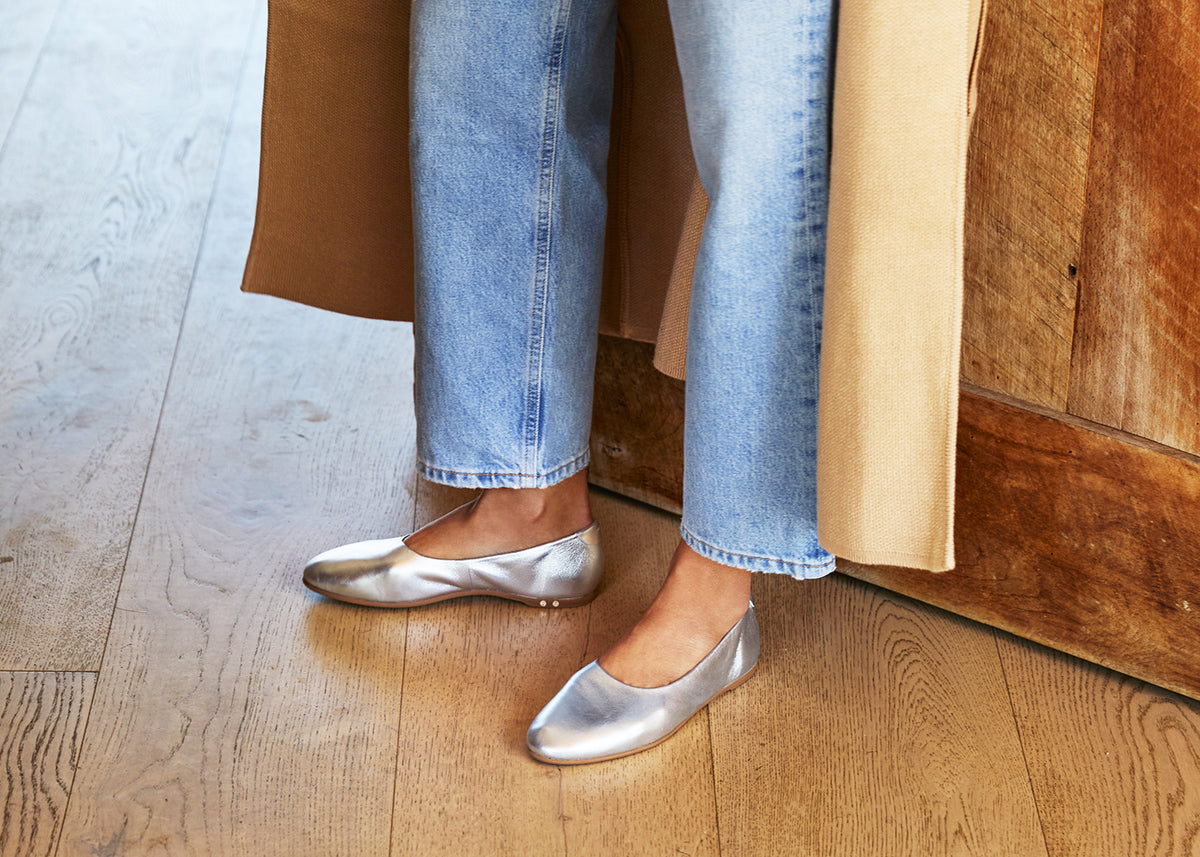 Woman wearing Swiftlet leather ballet slipper in silver with jeans and coat