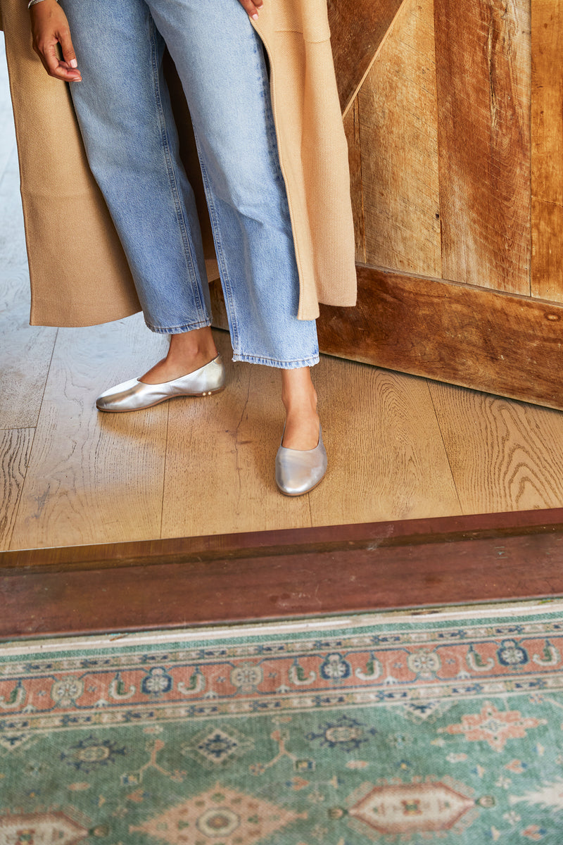 Woman wearing Swiftlet leather ballet slipper in silver with jeans and coat