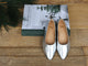Swoop leather ballet shoes in silver propped on a Christmas book.