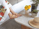Woman wearing Topaz leather slide sandals in honey with gold accents with white floral dress