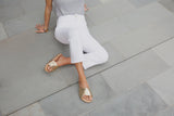 Woman wearing Tori leather slide sandals in gold/beach in white jeans and gray top.
