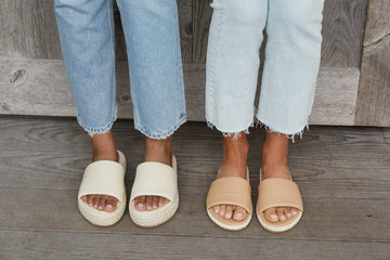 Women wearing Trumpeter Raffia platform sandals in eggshell and Puffbird Raffia slide sandals in beach with jeans.