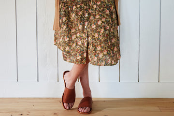 Woman wearing Weebill leather slide sandal in cognac with floral dress and cardigan.