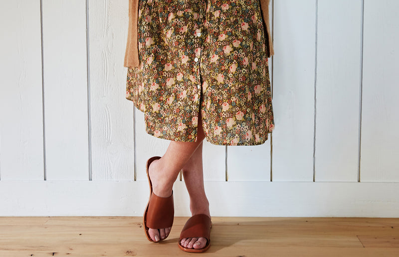 Woman wearing Weebill leather slide sandal in cognac with floral dress and cardigan.