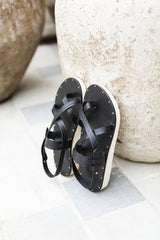 Wigeon burnished leather toe-ring sandal in black propped up on rock