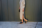 Woman wearing Woodpecker Shearling clogs in black with gray knit skirt and top.