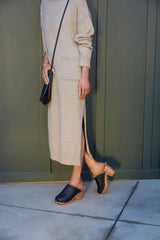 Woman wearing Woodpecker Shearling clogs in bronze/black with gray knit skirt and top.