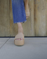 Woman wearing Albatross platform sandal in beach. Group shot of Albatross platform sandals in black, beach, eggshell/black 