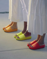 Women wearing Pelican leather platform sandals in flamingo, celery, papaya. Woman wearing Pelican sandal in honey. Group shot of Pelican sandals in platinum/beach, tangerine, lilac/beach, eggshell/beach, celery, papaya, hibiscus, honey.